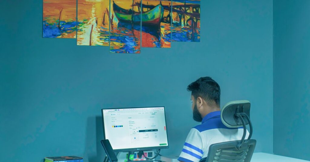 A man working on a desktop computer at home office with vibrant wall art.