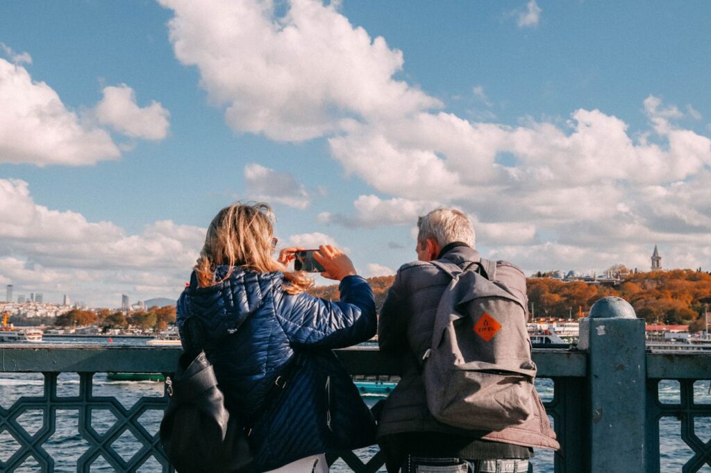 Two adults enjoying the view from a bridge, capturing scenic river sights under a vibrant sky.