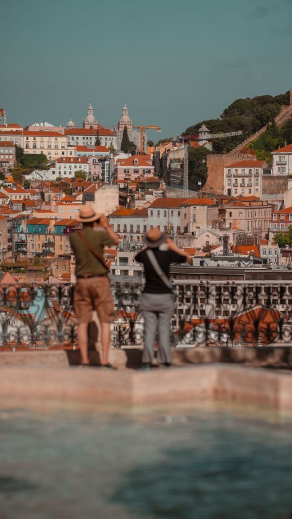 Tourists photograph the vibrant cityscape of Lisbon, Portugal on a sunny day.